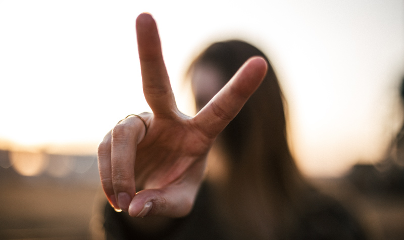 A woman holds two fingers up to represent biannual dental visits