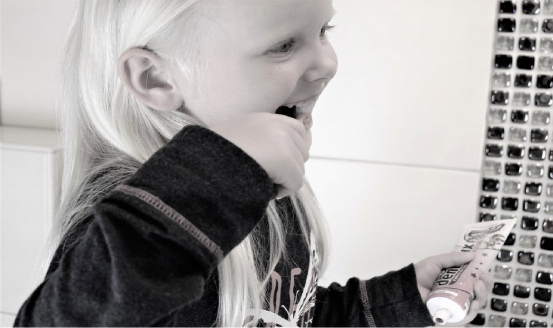 young blond girl brushing her teeth