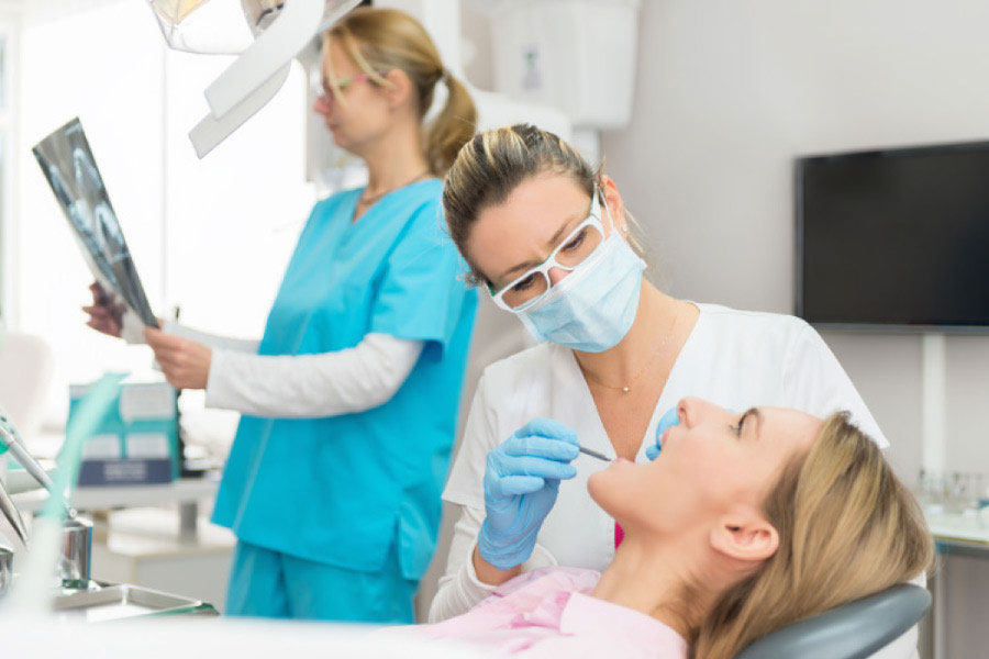 woman in the dental chair receiving a filling from a masked dental worker