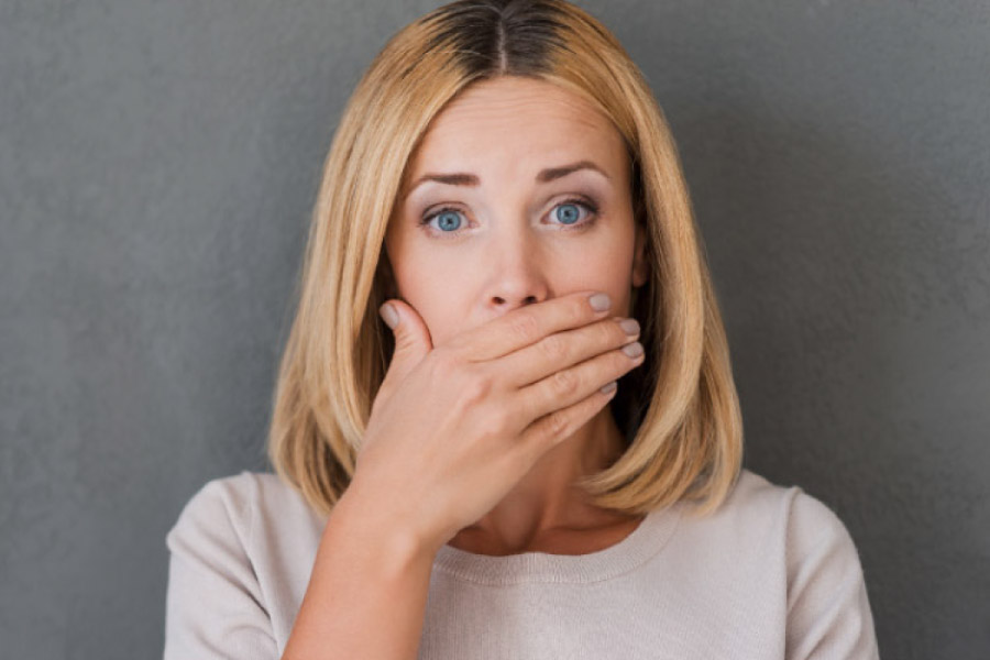 woman covers her mouth with her hand to hide bleeding gums