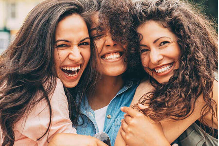three young women flash their brilliant smiles