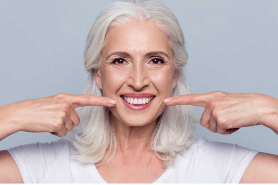 woman points to her teeth with both forefingers after professional teeth whitening