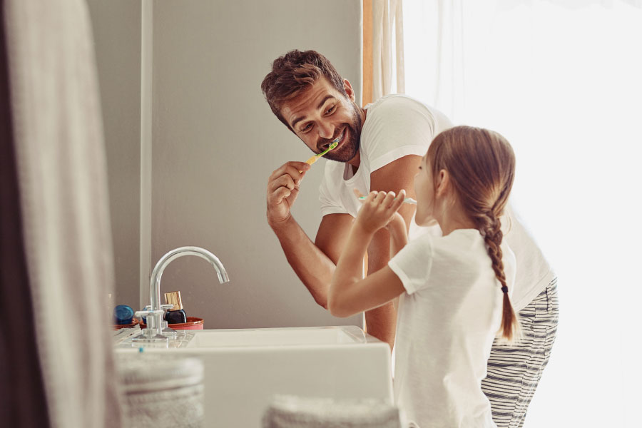 dad brushing his teeth with his young daughter