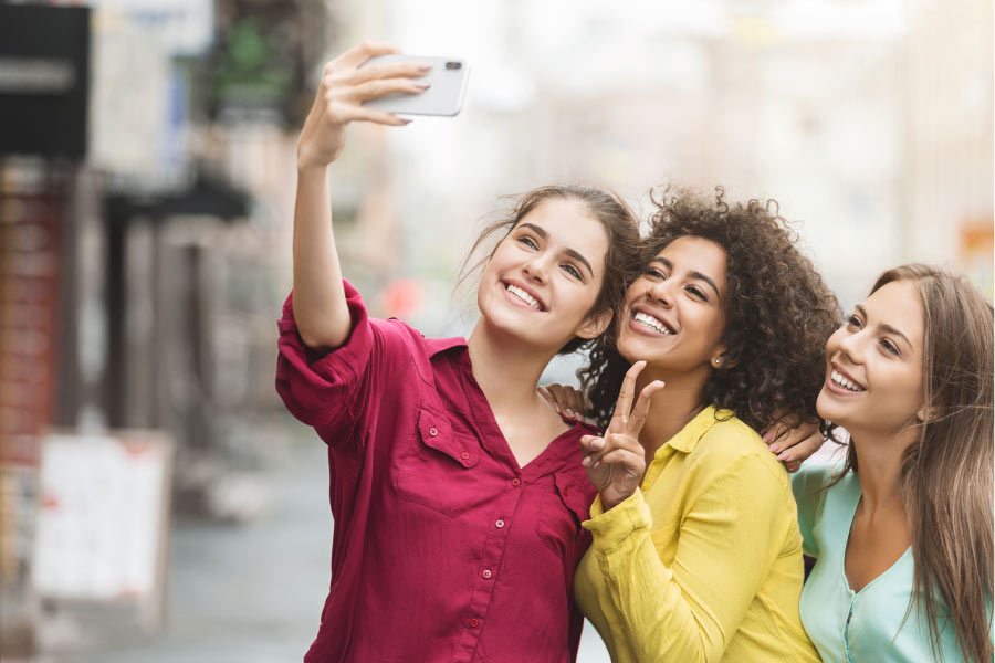 three young women take a selfie to show off their cosmetic dentistry smiles