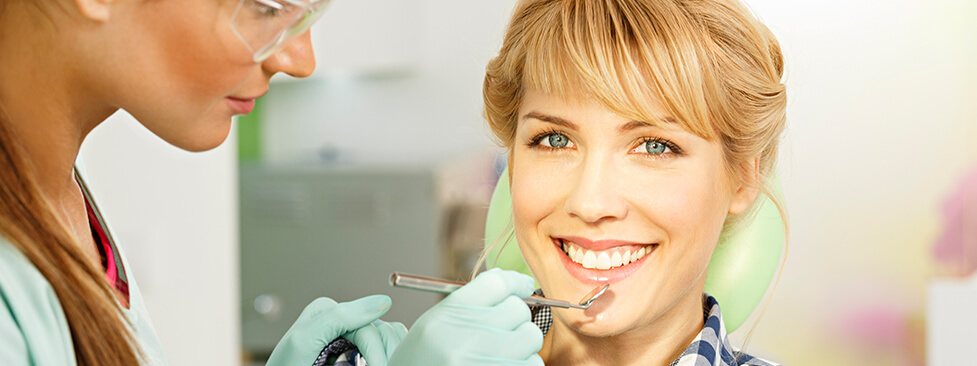 smiling woman having her teeth examined by a dentist