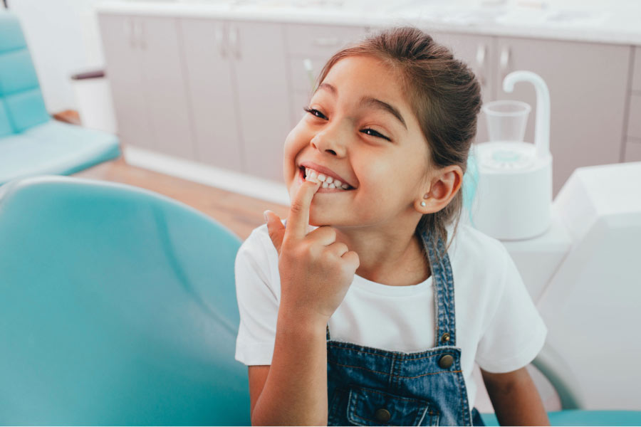 young girl points to her loose baby tooth