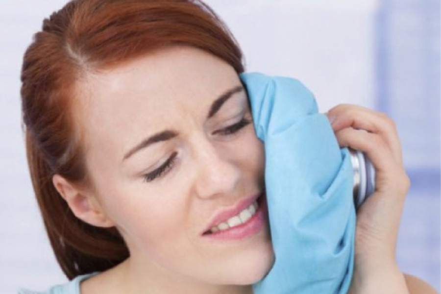 woman holding an icepack to her cheek after root canal therapy