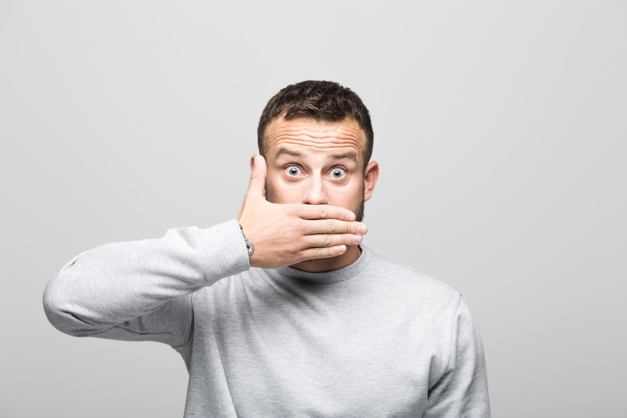 man with a surprised look holds his hand over his mouth